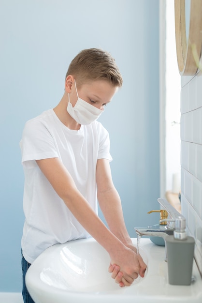 Foto gratuita chico en el baño lavándose las manos
