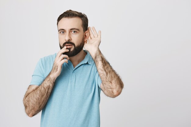 Chico barbudo intrigado escuchando a escondidas, tratando de escuchar una conversación