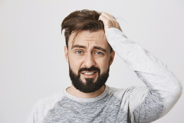 Chico barbudo con problemas en pánico lanzando el pelo y parece asustado