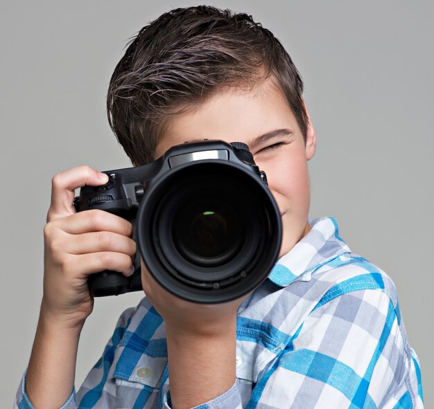 Chico con cámara réflex digital fotografiando. Muchacho adolescente con cámara tomando fotografías.