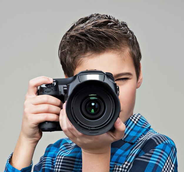 Chico con cámara réflex digital fotografiando. Muchacho adolescente con cámara tomando fotografías.