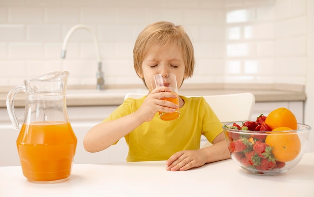 Foto gratuita chico en casa bebiendo jugo