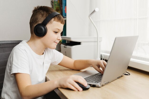 Chico a casa usando laptop y auriculares