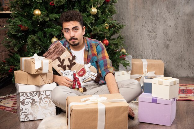 El chico en casual rodeado de regalos.