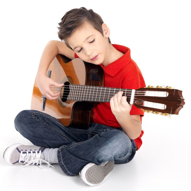 Chico caucásico está tocando la guitarra acústica, aislada