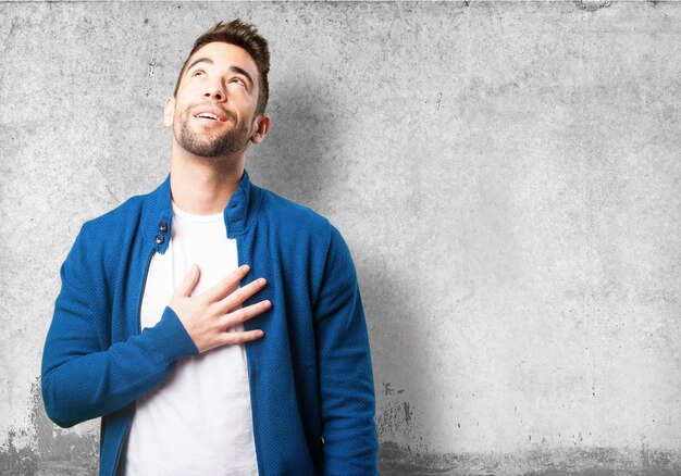 Chico con chaqueta azul con la mano en el corazón