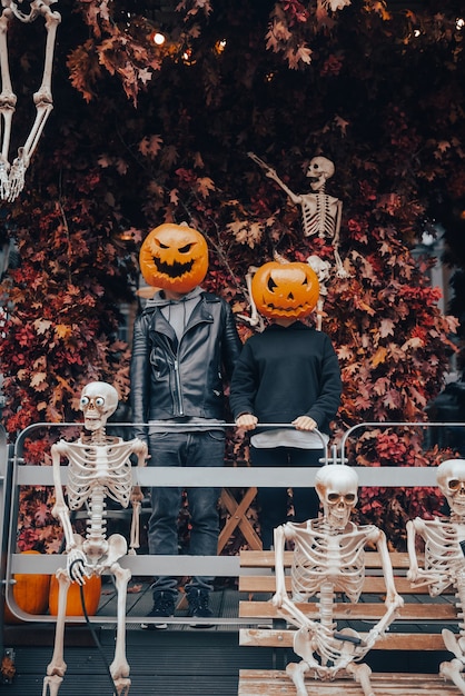 Un chico y una chica con cabezas de calabaza posando en la calle.