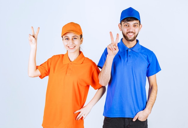 Foto gratuita chico y chica mensajero con uniformes azules y amarillos que muestran el signo de disfrute y felicidad.