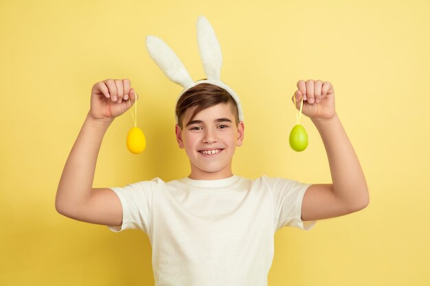 Chico como un conejito de Pascua en la pared amarilla del estudio