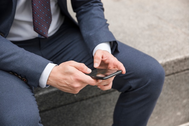 Chico de cultivo en traje de navegación smartphone en la calle