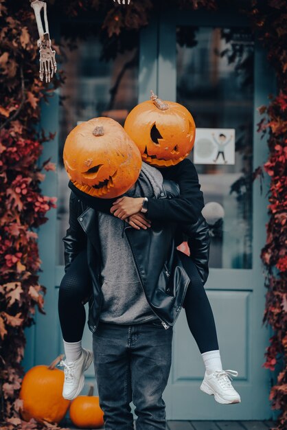 Chico dando a su novia un paseo en caballito ambos con cabezas de calabaza