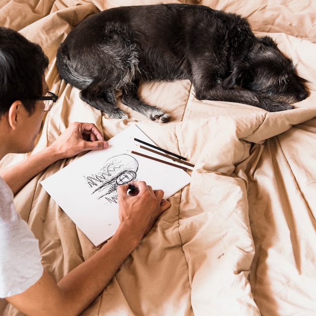 Foto gratuita chico dibujando con carboncillo con perro