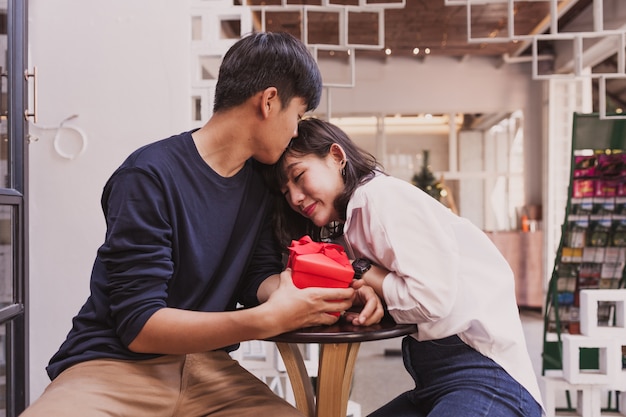 Chico enamorado con un regalo rojo mirando a su novia