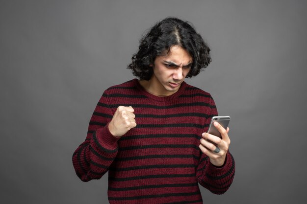 Un chico se enoja mientras usa un teléfono inteligente