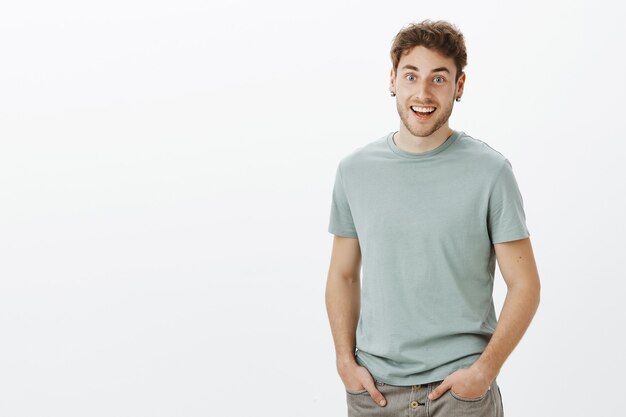 Chico escuchando noticias increíbles, sintiéndose feliz por un amigo. Retrato de hombre guapo de aspecto amable positivo en camiseta