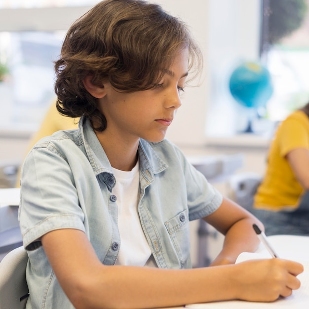 Foto gratuita chico en la escuela escribiendo