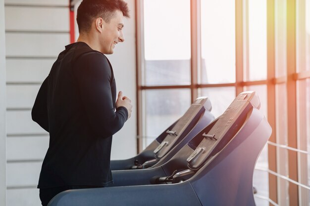 Chico con estilo en el gimnasio está entrenando en la cinta. Estilo de vida saludable.