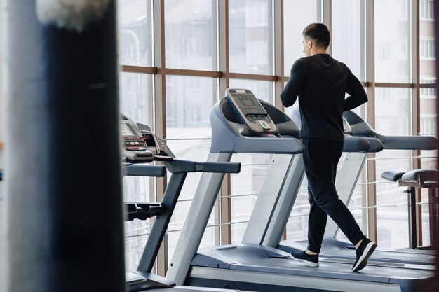 Chico con estilo en el gimnasio está entrenando en la cinta. Estilo de vida saludable.