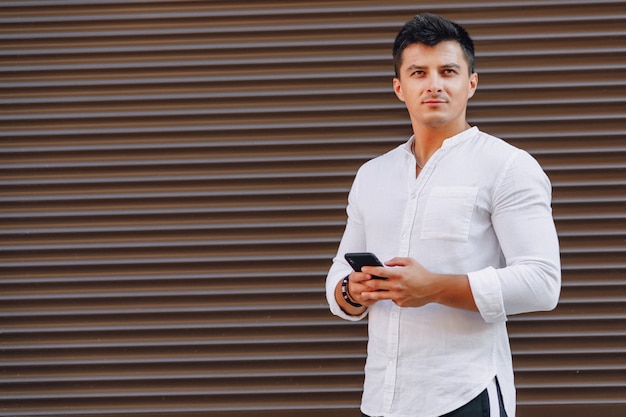 Chico con estilo joven en camisa escribiendo en el teléfono en simple