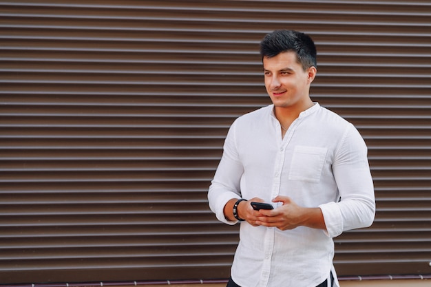 Chico con estilo joven en camisa escribiendo en el teléfono