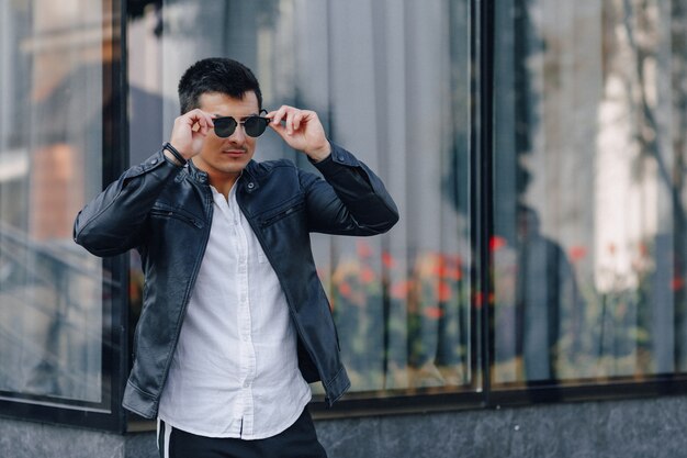 Chico con estilo joven con gafas en chaqueta de cuero negro