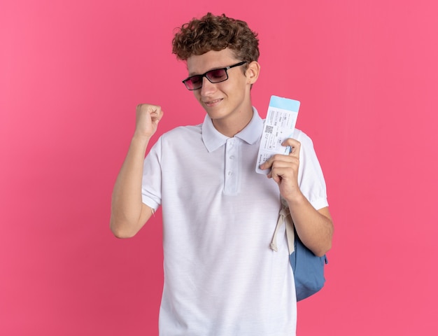 Chico estudiante en ropa casual con gafas con mochila con billetes de avión