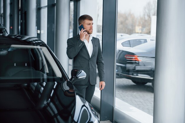 Chico exitoso. Empresario barbudo con estilo moderno en el salón del automóvil