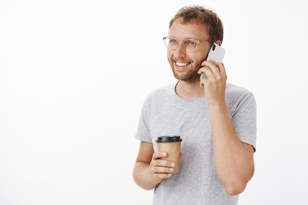 Chico feliz amistoso hablando por teléfono y tomando café