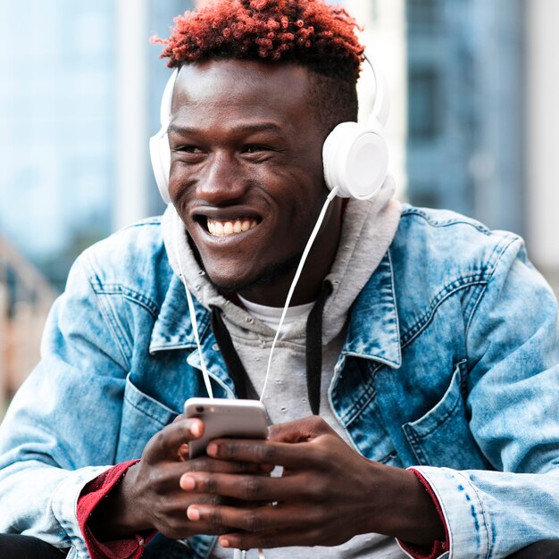 Foto gratuita chico feliz de tiro medio con auriculares y teléfono inteligente