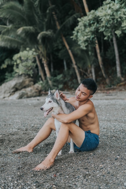 Foto gratuita chico filipino guapo adolescente jugando con su mascota husky siberiano