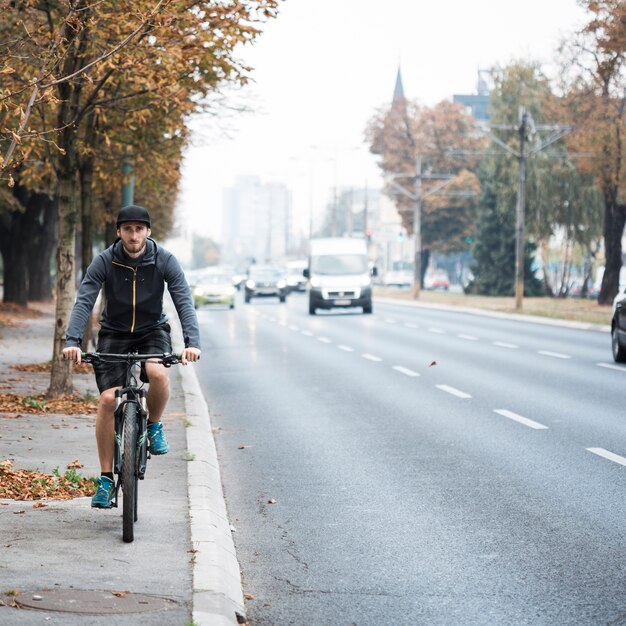 Chico fitness con bicicleta en la carretera