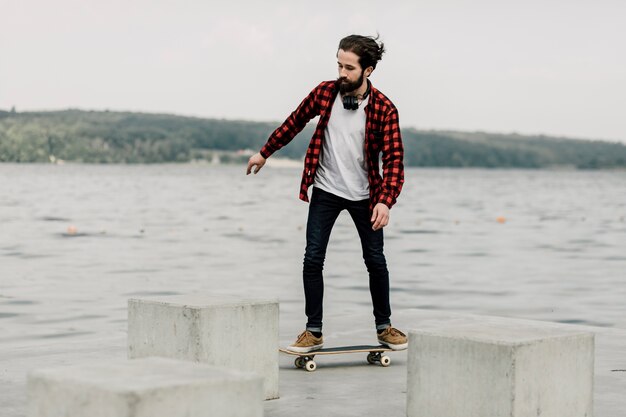 Chico en franela en patineta por un lago