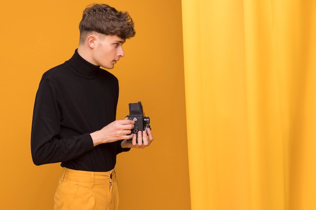 Chico grabando con un camcorder en un escenario amarillo