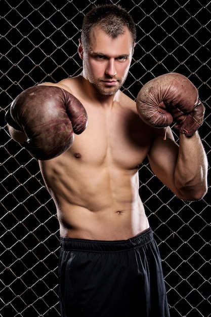 Chico con guantes de boxeo mostrando músculos en la valla