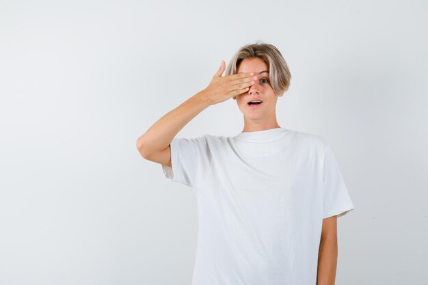 Chico guapo adolescente en una camiseta blanca que cubre su ojo