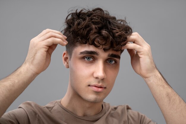 Chico guapo arreglándose el pelo rizado