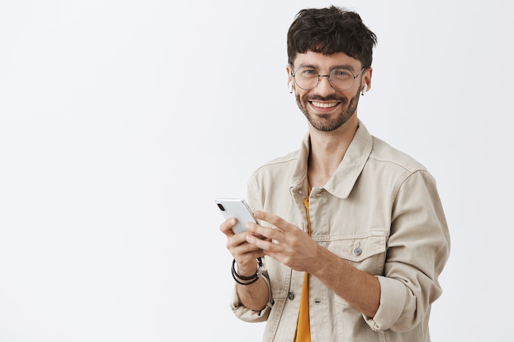 Foto gratuito chico guapo con barba elegante posando contra la pared blanca