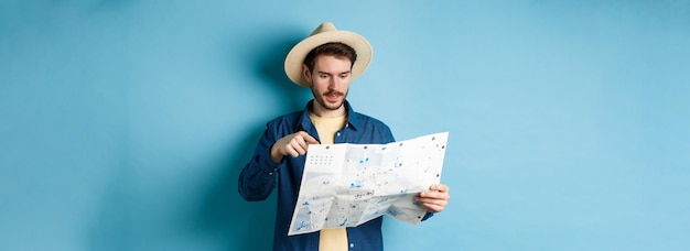 Chico guapo eligiendo un lugar para ir señalando el mapa turístico de vacaciones viajando en vacaciones de verano