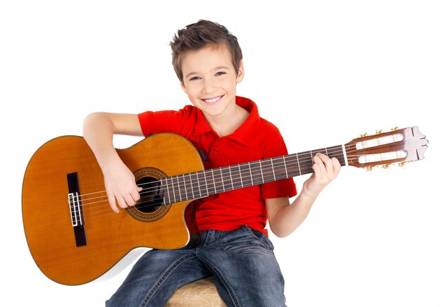 Chico guapo feliz está tocando la guitarra acústica aislada en blanco