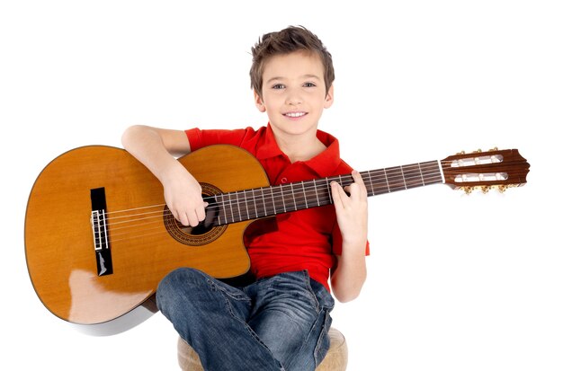 Chico guapo feliz está tocando la guitarra acústica aislada en blanco