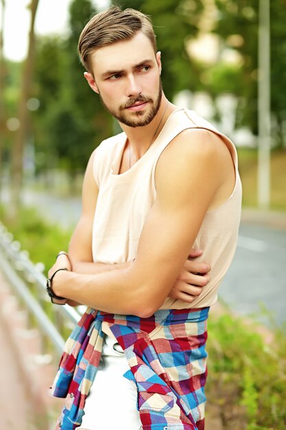 Chico guapo hipster en ropa de verano elegante posando en la calle