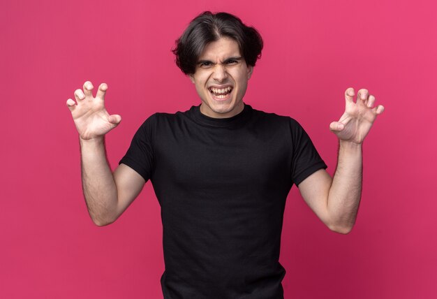 Chico guapo joven alegre con camiseta negra haciendo gesto de estilo tigre aislado en la pared rosa
