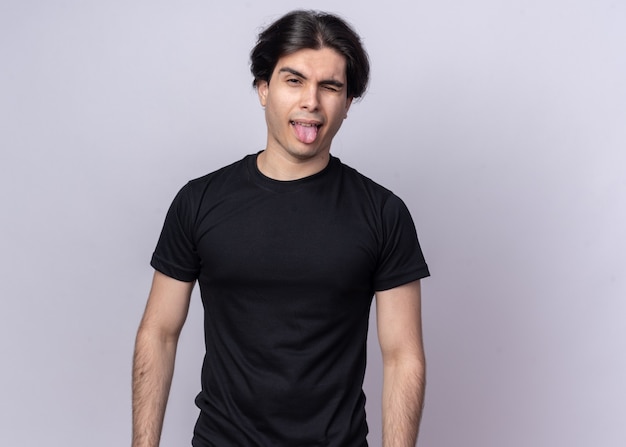 Foto gratuita chico guapo joven alegre con camiseta negra que muestra la lengua aislada en la pared blanca