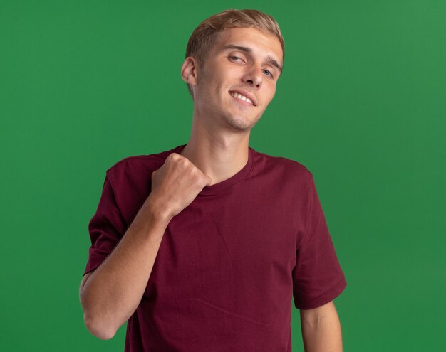 Chico guapo joven calentado con camisa roja sosteniendo el collar aislado en la pared verde