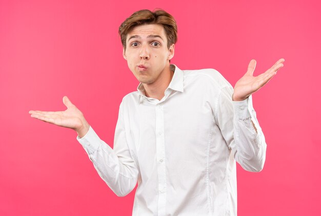 Chico guapo joven confundido con camisa blanca extendiendo las manos