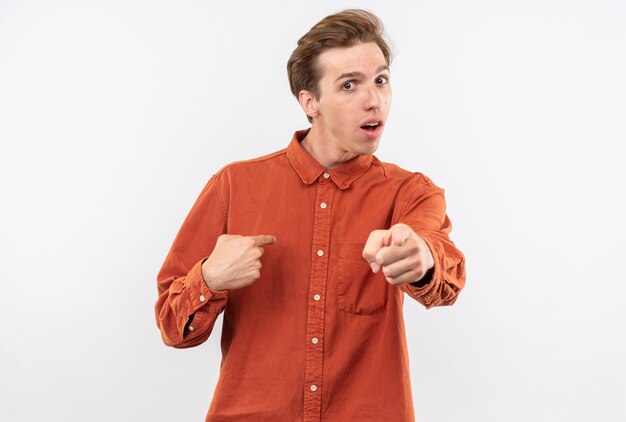 Chico guapo joven confundido con puntos de camisa roja a sí mismo mostrando gesto