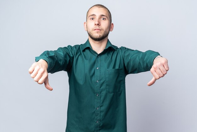 Chico guapo joven disgustado con camisa verde mostrando los pulgares hacia abajo