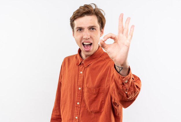 Chico guapo joven emocionado con camisa roja mostrando gesto bien