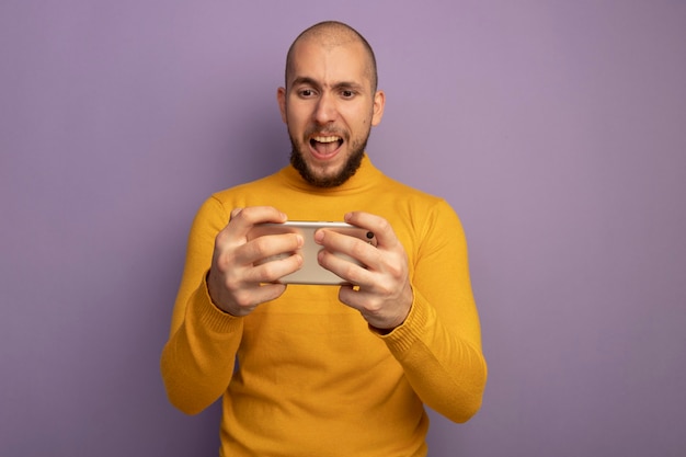 Chico guapo joven enojado jugando en el teléfono