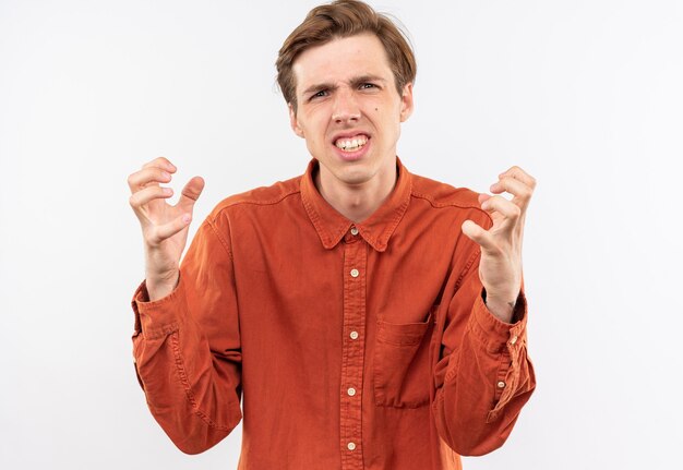 Chico guapo joven molesto con camisa roja cogidos de la mano alrededor de la cara aislada en la pared blanca